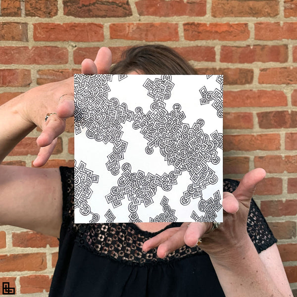 Photo of a human holding this specific LLLinked square. The lines of LLLinked are drawn by hand. Each square is 6"x6", cut, labeled, signed, and stamped by hand. Each LLLinked square has a unique QR code/RFID label. No two squares are the same. Owners can register and connect with other owners at LLLinked.art.