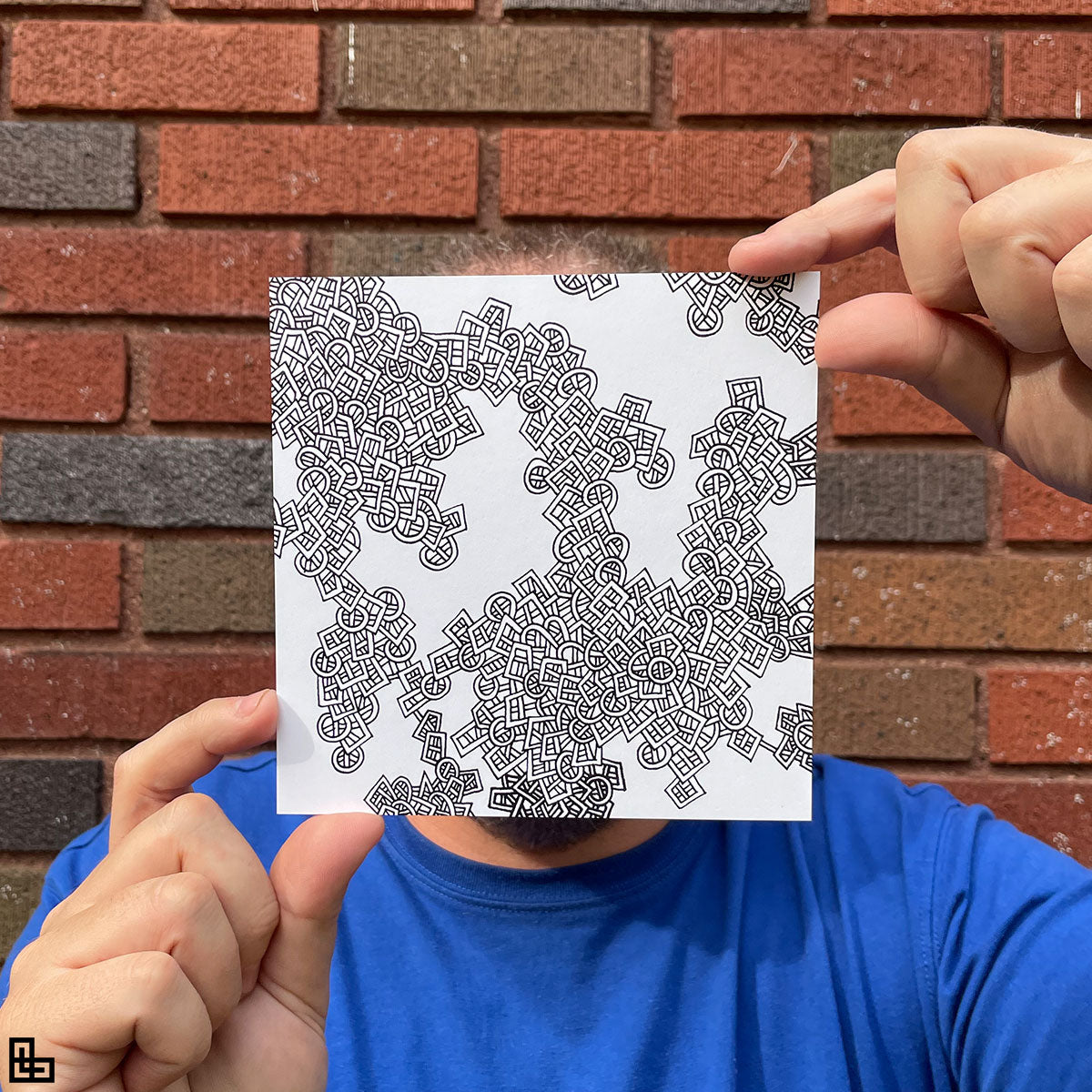 Photo of a human holding this specific LLLinked square. The lines of LLLinked are drawn by hand. Each square is 6"x6", cut, labeled, signed, and stamped by hand. Each LLLinked square has a unique QR code/RFID label. No two squares are the same. Owners can register and connect with other owners at LLLinked.art.